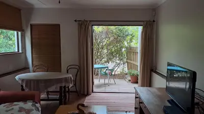 a living room with a door open to a patio at Martha's Place in Gordonʼs Bay