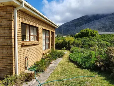 a house with a green hose outside of it at Betty's Bay Quaint Cottage in Bettyʼs Bay