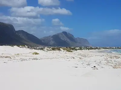 a sandy beach with mountains in the background at Betty's Bay Quaint Cottage in Bettyʼs Bay