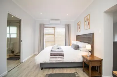 a white bedroom with a bed and a bathroom at Lin's Snooze Inn in Strand