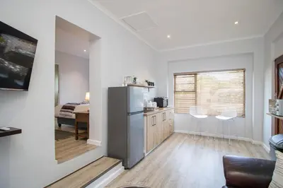 a kitchen with a refrigerator and a dining room at Lin's Snooze Inn in Strand