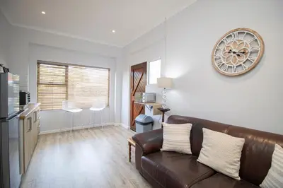 a living room with a couch and a clock on the wall at Lin's Snooze Inn in Strand