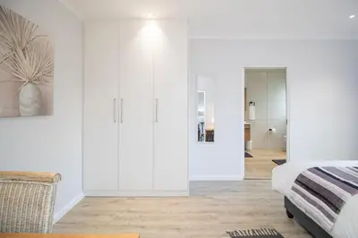 a bedroom with white walls and a bed and a mirror at Lin's Snooze Inn in Strand