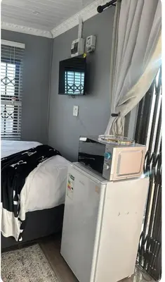 a bedroom with a bed and a refrigerator and a microwave at Malithabo in Khayelitsha
