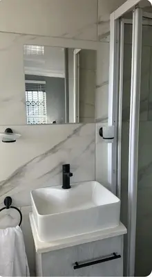a bathroom with a white sink and a mirror at Malithabo in Khayelitsha