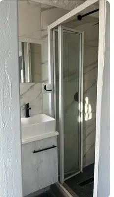 a bathroom with a white sink and a shower at Malithabo in Khayelitsha