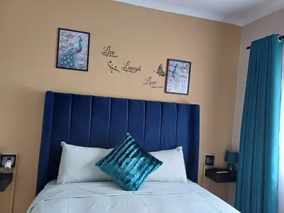 a bed with a blue headboard in a bedroom at Oakway Guest Suite 2 Beds 1Bath Aircon Kitchen Private in Kuilsrivier