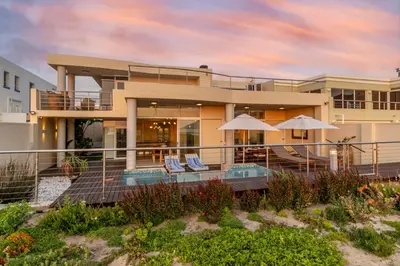 a house on the beach with chairs and umbrellas at 