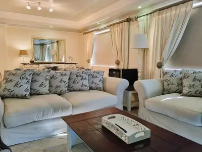a living room with a white couch and a table at 'Goldwater on Beach' - 3 Bedroom Beachfront with Balcony & BBQ - Sleeps 6 in Gordonʼs Bay