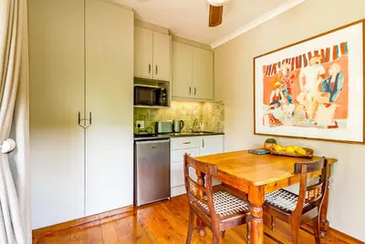 a kitchen with a wooden table with two chairs and a wooden floor at 5 on Paul Kruger in Somerset West
