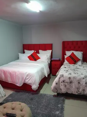 a bedroom with two beds with red headboards at Fairbridge Queens and Kings Guest House in Cape Town