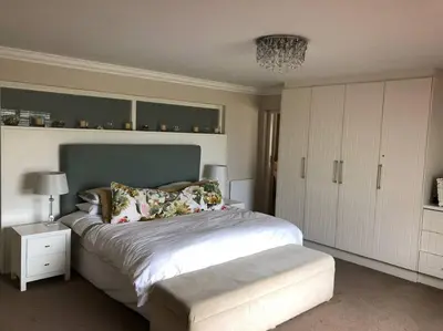 a bedroom with a large bed and a white cabinet at Onrus Home with a Sea View in Hermanus