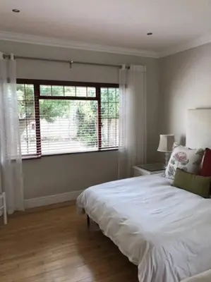 a bedroom with a white bed and a large window at Onrus Home with a Sea View in Hermanus