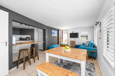 a kitchen and living room with a table and a couch at Suikerbossie 83 in Cape Town
