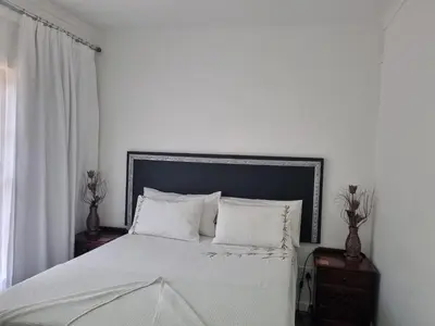 a bedroom with a bed with white sheets and pillows at Somerset west Stay 1 in Somerset West