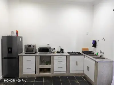 a kitchen with white cabinets and a black refrigerator at Somerset west Stay 1 in Somerset West