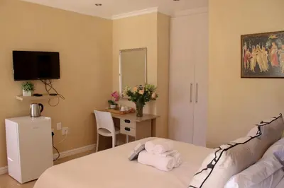 a bedroom with a bed and a desk with a mirror at Tygerviews on Uys in Tygerberg Hills