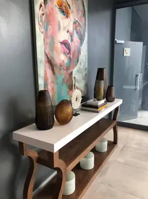 a table with vases and a painting of a man at Luxury Three Bedroom Axis- Ocean and Mountain Views in Cape Town