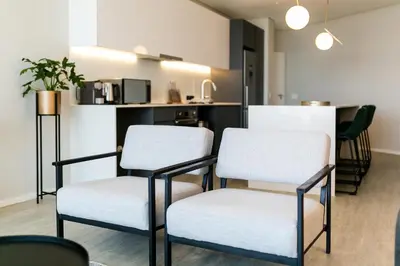 a room with two white chairs and a kitchen at Luxury Three Bedroom Axis- Ocean and Mountain Views in Cape Town