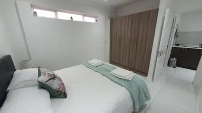 a white bedroom with a bed with two towels on it at Comfey Stay in Somerset West