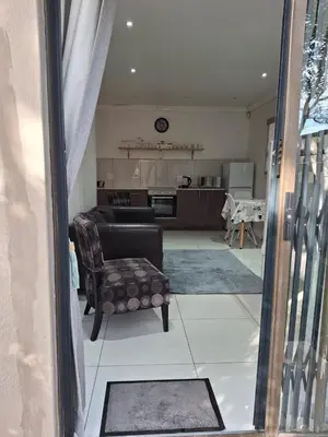 a living room with a chair and a kitchen at Comfey Stay in Somerset West
