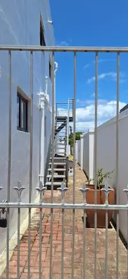 a metal fence with a potted plant next to a building at 33 on Vermont in Hermanus