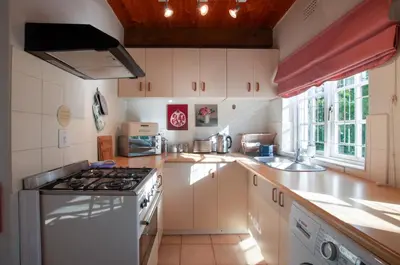 a kitchen with white cabinets and a stove top oven at Serendipity Self-Catering Cottage in Greyton