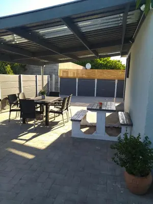 a patio with a table and chairs under awning at 60 On Kosmos in Bellville South