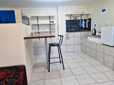 a kitchen with a table and a stool in a room at 22 on Shiraz in Hoheizen