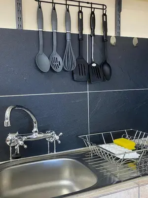 a kitchen counter with a sink and utensils hanging on a wall at 22 on Shiraz in Hoheizen