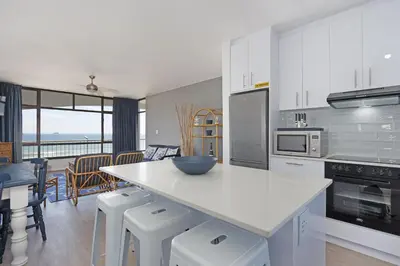 a kitchen with a counter and a table with chairs at Witsand 303 in Cape Town