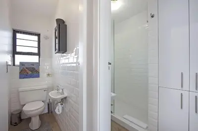 a white bathroom with a toilet and a shower at Witsand 303 in Cape Town