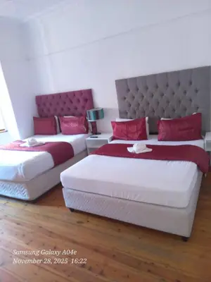 two beds with red pillows in a bedroom at Neo & ruks guest houses Boston Belleville 4 in Bellville