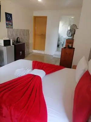 a large white bed with a red blanket on it at Neo & ruks guest houses Boston Belleville 4 in Bellville