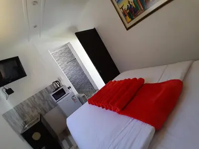 a bedroom with a white bed with a red blanket at Neo & ruks guest houses Boston Belleville 4 in Bellville