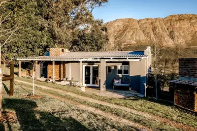 a small blue house with a mountain in the background at Courchevel Cottages in Franschhoek