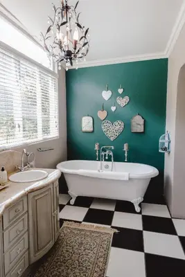 a bathroom with a white tub and a green wall at Courchevel Cottages in Franschhoek