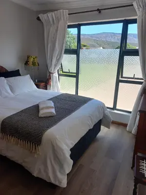 a bedroom with a bed and a large window at Rosa Villa in Hermanus
