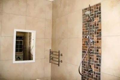 a bathroom with a shower with a mirror at Firehouse selfcatering Garden Cottage no 1 in Wellington