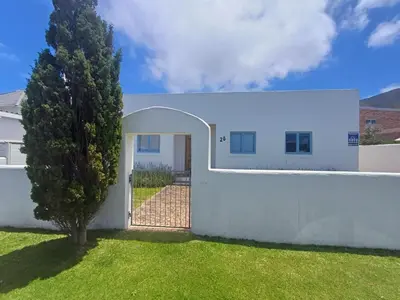 a white house with a tree in the yard at Holiday Vibe in Hermanus