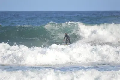 a man riding a wave on a surfboard in the ocean at PROVIDENCE VILLA -Tranquil, Neat & Private Cottage in Hermanus