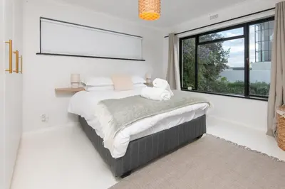 a bedroom with a bed and a large window at Fun in the Voelklip Sun in Hermanus