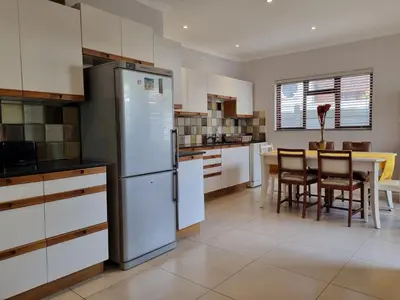 a kitchen with a refrigerator and a table with chairs at 'Country Beach House' - Traditional Family Vacation Home for 6 - Near Beach in Gordonʼs Bay