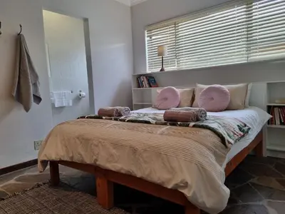 a bedroom with a bed with pink pillows and a window at 'Country Beach House' - Traditional Family Vacation Home for 6 - Near Beach in Gordonʼs Bay