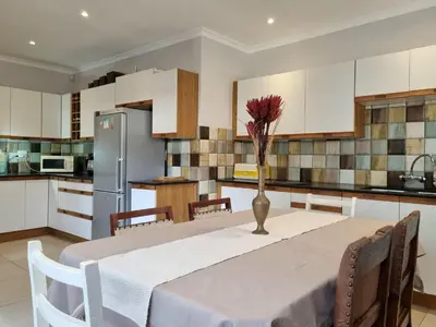 a kitchen with a table with a vase of flowers on it at 'Country Beach House' - Traditional Family Vacation Home for 6 - Near Beach in Gordonʼs Bay