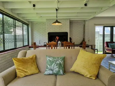 a couch in a living room with a fireplace at 'Country Beach House' - Traditional Family Vacation Home for 6 - Near Beach in Gordonʼs Bay
