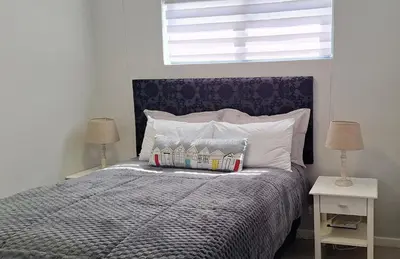 a bedroom with a bed with two lamps and a window at Sound of the surf in Cape Town