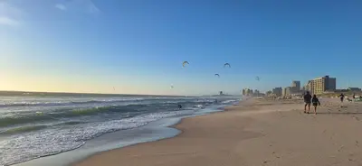 a beach with people walking on the sand and the ocean at Sound of the surf in Cape Town