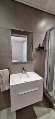 a bathroom with a white sink and a mirror at Sound of the surf in Cape Town