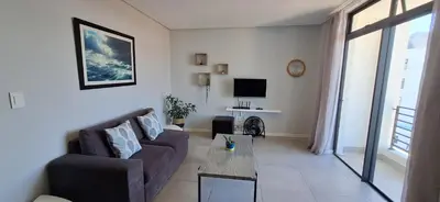 a living room with a couch and a tv at Sound of the surf in Cape Town
